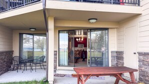 A patio with a wooden table and chairs, a glass door leading to an interior space, and a stone wall on one side. - `The Alice` in Ideal Beach Resort (Garden City)