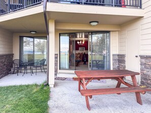 A patio with a wooden table and chairs, a glass door leading to an interior space, and a stone wall on one side. - `The Alice` in Ideal Beach Resort (Garden City)