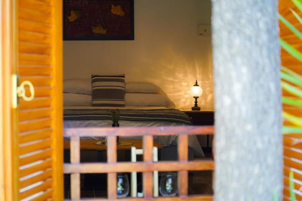 A bedroom with a bed, a nightstand, a lamp, and a wall-mounted artwork.