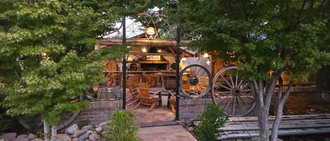 A rustic outdoor seating area with wooden furniture and a large wooden wheel structure.