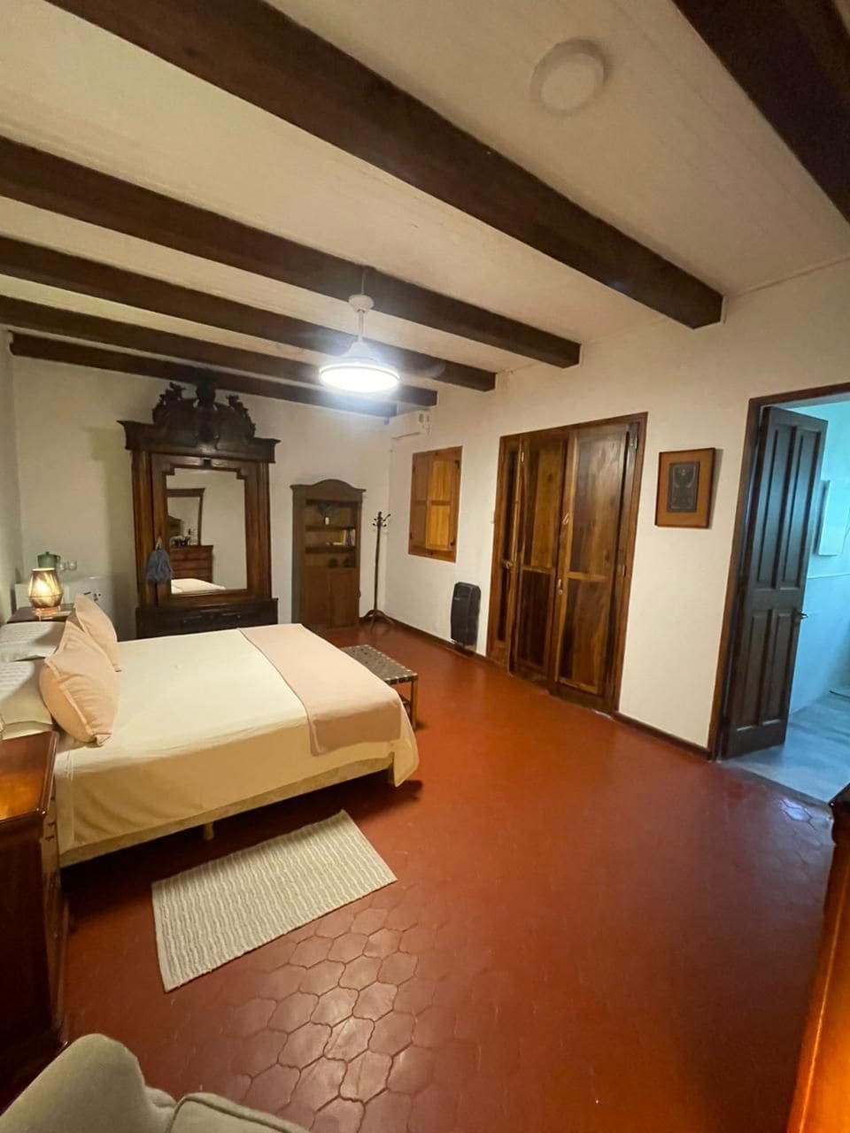 A bedroom with a bed, wooden wardrobe, and a mirror.