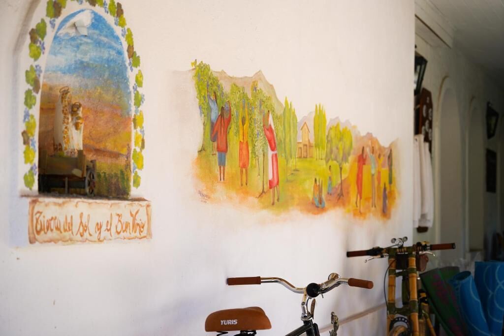 Un mur orné de deux tableaux, un vélo et une fenêtre donnant sur un immeuble.