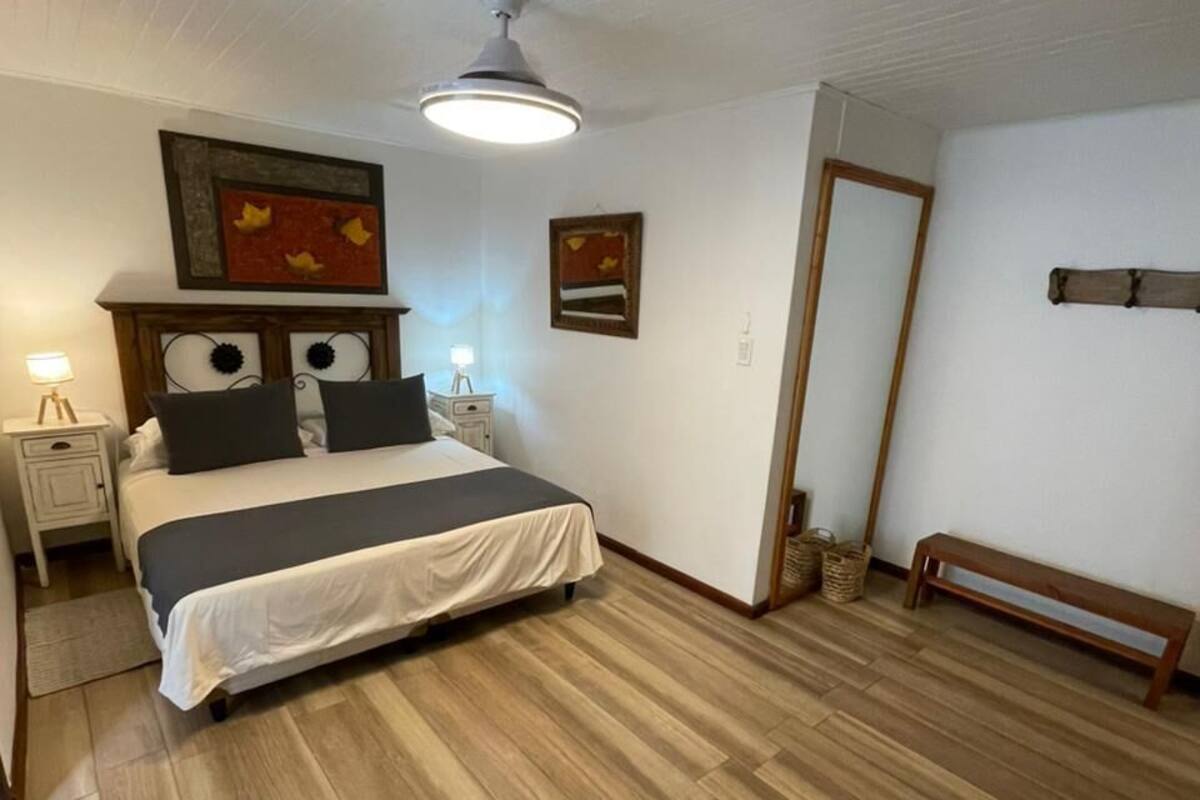 A bedroom with a bed, bedside tables, a ceiling fan, and a wooden floor.