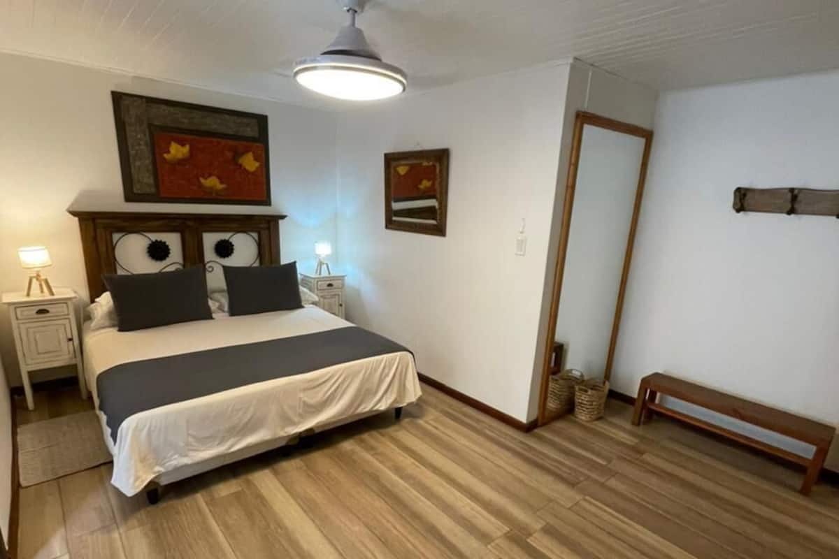 A bedroom with a bed, bedside tables, a ceiling fan, and a wooden floor.