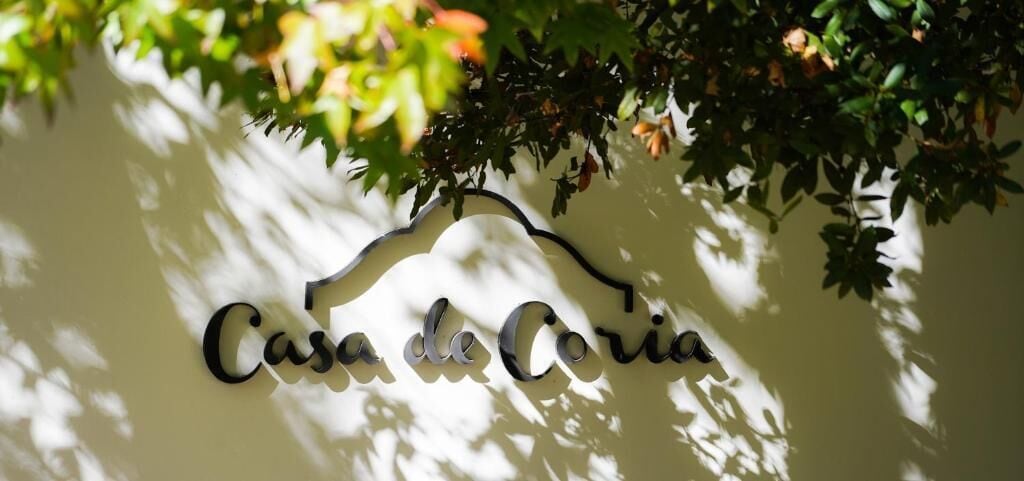 A wall-mounted sign with the text 'Casa de Coria' in a stylized font.