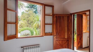 Une chambre avec une grande fenêtre, une porte en bois et un radiateur.