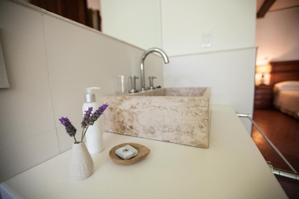A bathroom with a marble sink, a white vase with lavender flowers, and a soap dish.