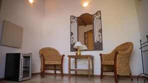 A room with two wicker chairs, a small table with a lamp, a refrigerator, and a wall-mounted mirror. - Casa de Coria (Chacras de Coria)