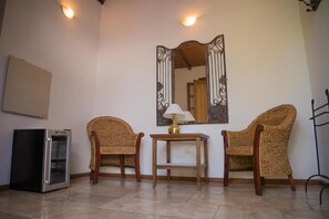 A room with two wicker chairs, a small table with a lamp, a refrigerator, and a wall-mounted mirror. - Casa de Coria (Chacras de Coria)