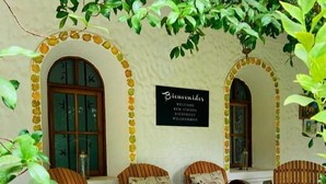 A cozy outdoor seating area with wooden barrels and cushioned chairs, a 'Bienvenidos' sign, and a rustic wall. - Casa de Coria (Chacras de Coria)