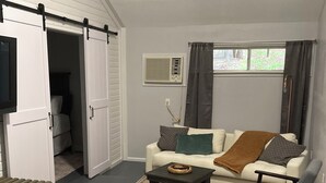 A living room with a white sofa, a coffee table, a dark armchair, a sliding door, and a window with curtains. - Sweetdillatpicklesgap (Conway)