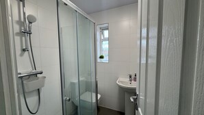 Ein modernes Badezimmer mit einer Duschkabine, einer Toilette und einem Waschbecken.