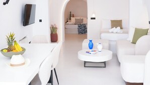 A modern, white-themed living area with a dining table, chairs, a sofa, and a coffee table. - Eros suites Oia (Oia)