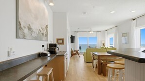 Una cocina moderna con barra, taburetes de madera y vistas al mar.
