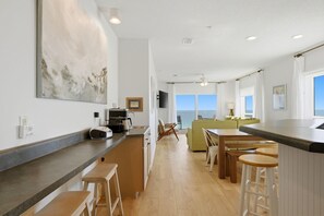 Eine moderne Küche mit Bar, Holzstühlen und Meerblick.