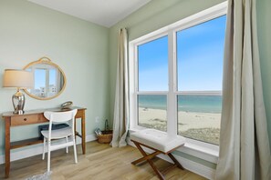 Ein Zimmer mit Schreibtisch, Stuhl und einem großen Fenster mit Blick auf den Strand.