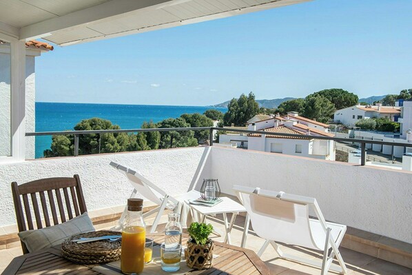 A balcony with a table, chairs, and a view of the sea and buildings. - Designed Costa Brava flat with panoramic sea views (Girona)
