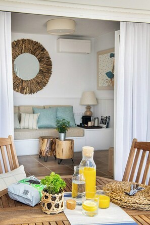 A cozy living room with a sofa, a coffee table with drinks, a plant, and a decorative mirror. - Designed Costa Brava flat with panoramic sea views (Girona)