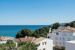 A coastal residential area with white buildings, red-tiled roofs, and a view of the sea. - Designed Costa Brava flat with panoramic sea views (Girona)