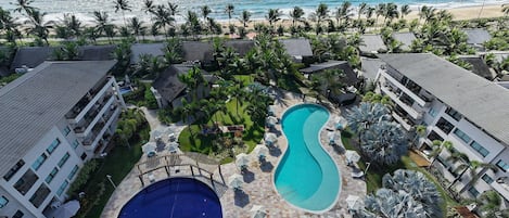 A resort with multiple swimming pools, a beach view, and tropical landscaping.