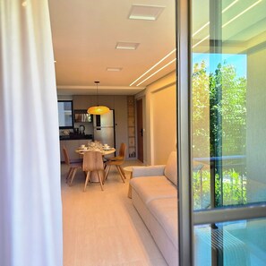 Ein modernes Interieur mit Essbereich, einer Couch und Blick durch eine Glastür.