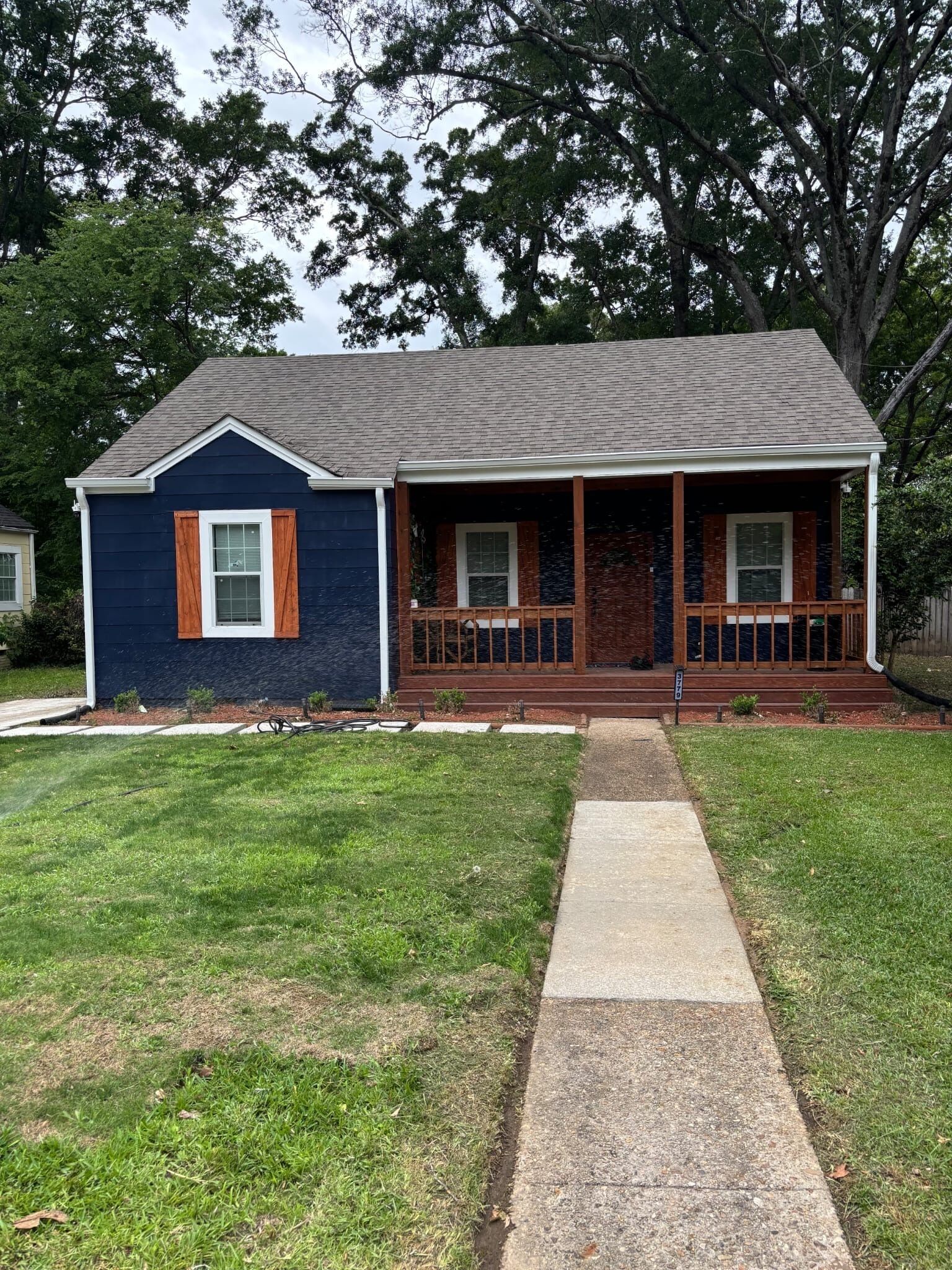 A single-story house with a front porch, a small front yard, and a sidewalk leading to the entrance.