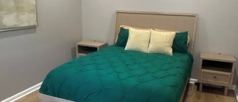 A bedroom with a bed, nightstands, a ceiling fan, and a wall-mounted artwork.