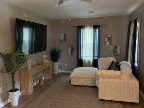 A living room with a sofa, a TV, a plant, and artwork on the walls.