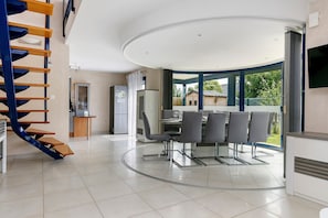 Una cocina moderna con comedor, una escalera en espiral y vistas al exterior.