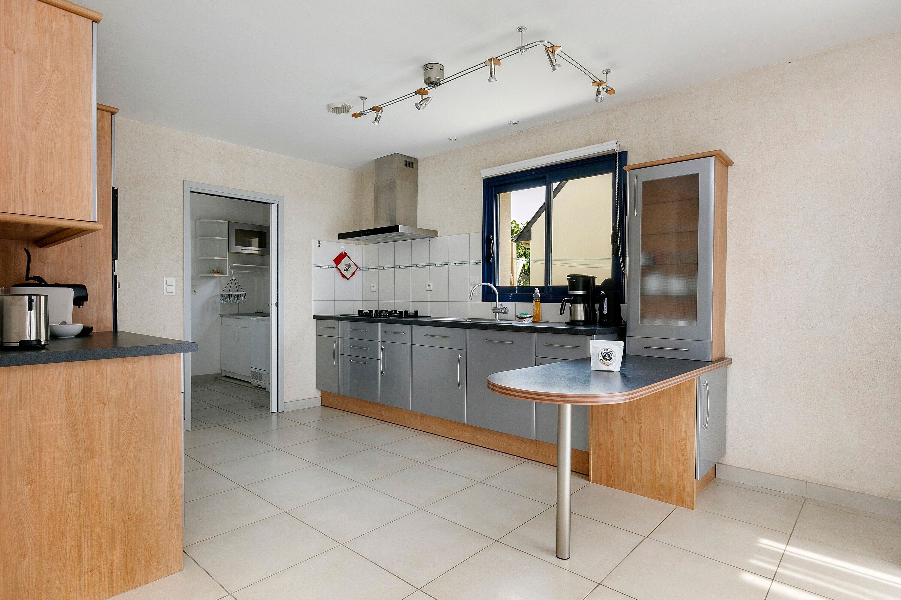 A modern kitchen with grey cabinets, a stainless steel range, and a wooden island.