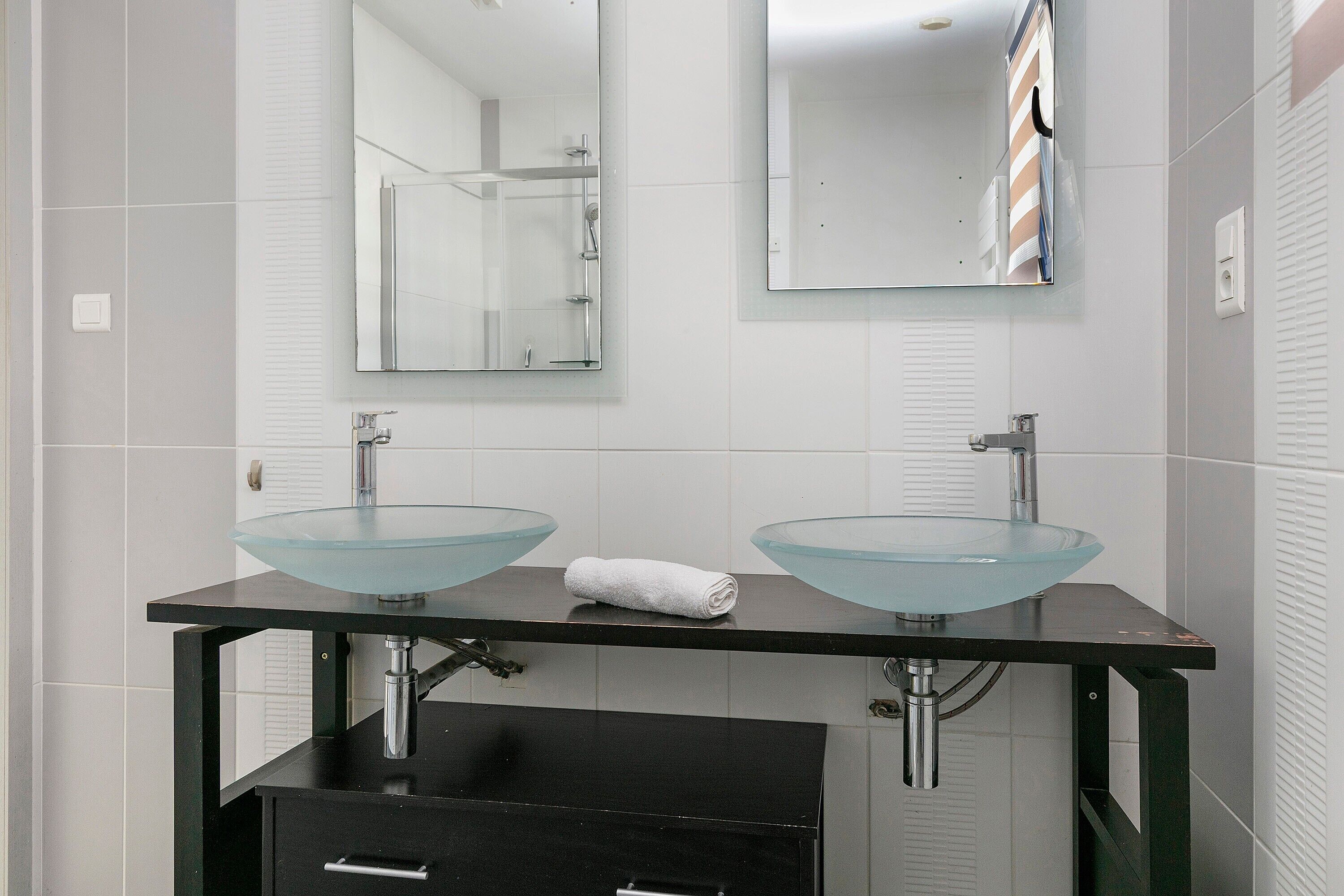 A bathroom with two glass sinks, a towel, and a mirror.