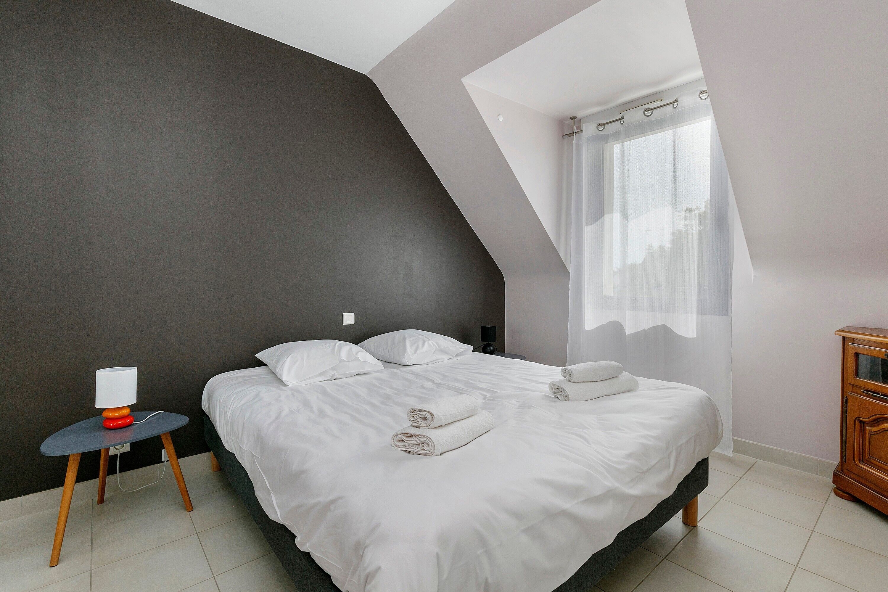 A bedroom with a bed, bedside table, and a nightstand.
