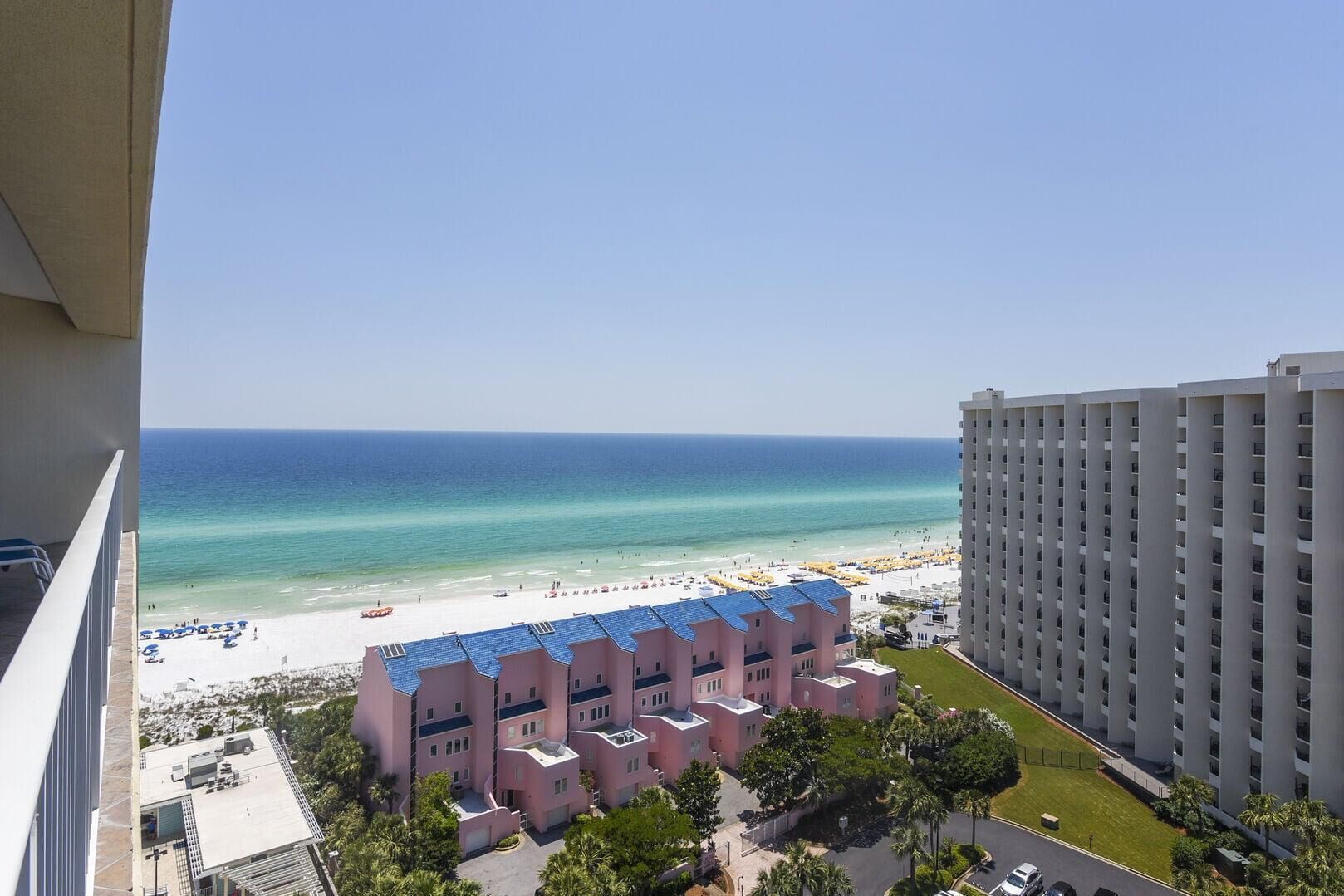 A hotel with a beach view, multiple floors, and a parking area.