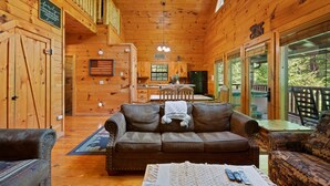 Ein Holzblockhaus-Interieur mit Wohnbereich, Essbereich und großen Fenstern.