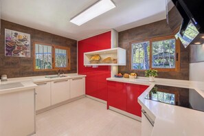 Une cuisine moderne avec des meubles rouges, un plan de travail blanc et un four encastré.