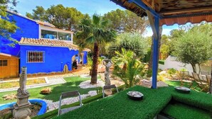 Ein blaues Haus mit Garten, einer Statue und einer Pergola.