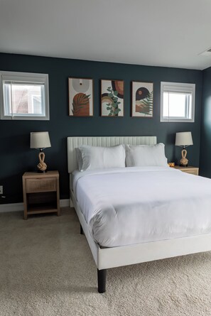 A bedroom with a bed, two nightstands, and three wall-mounted paintings. - Boho 3BR Near Stadiums + Uptown w/ Garage (Charlotte)