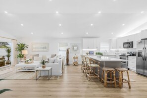 A modern kitchen with white cabinets, stainless steel appliances, and a central island with bar stools. - A Touch of Heaven • Heated Pool • Near Beach (Naples)
