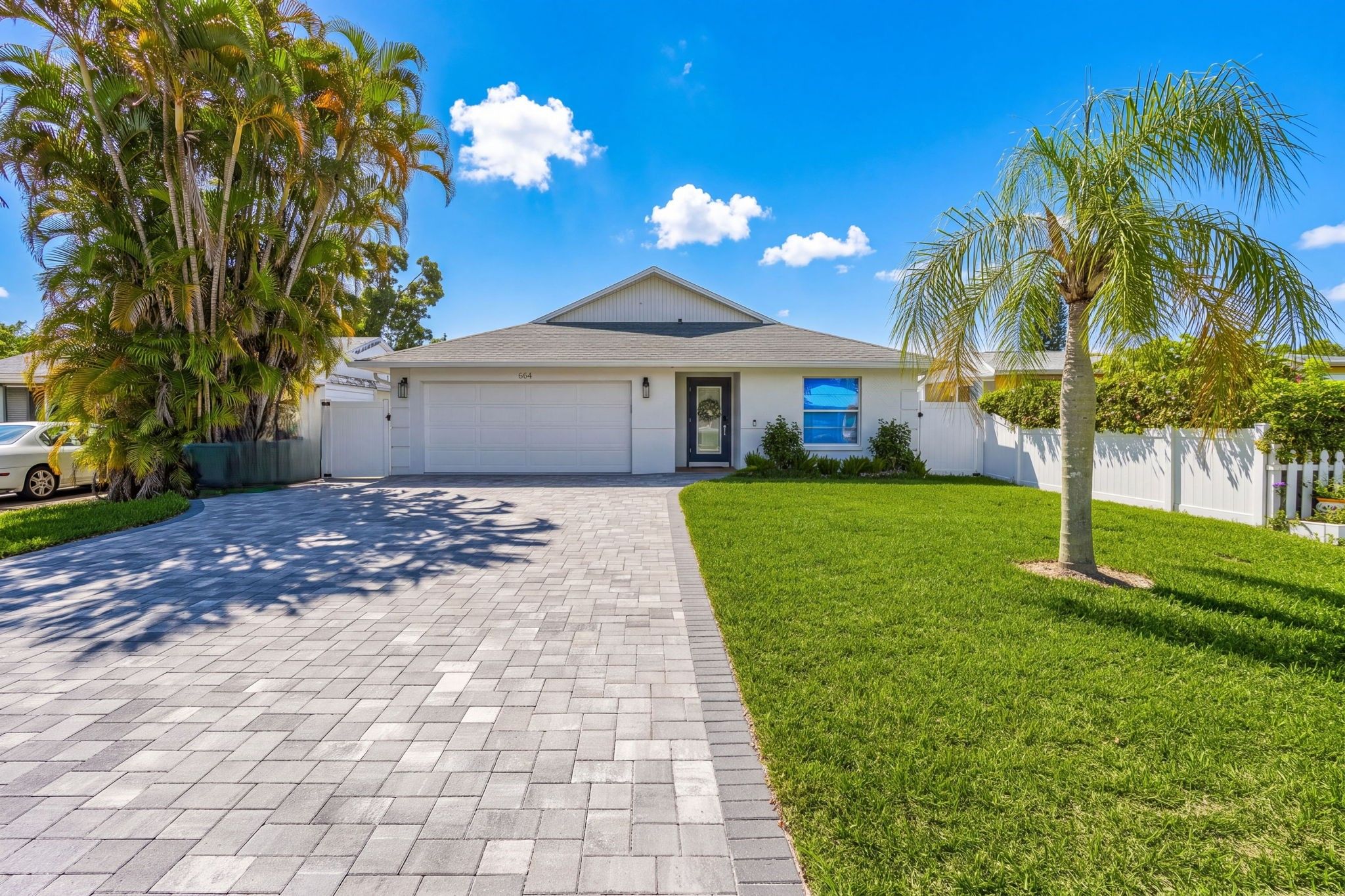 A single-story house with a garage, a paved driveway, and a well-maintained lawn.