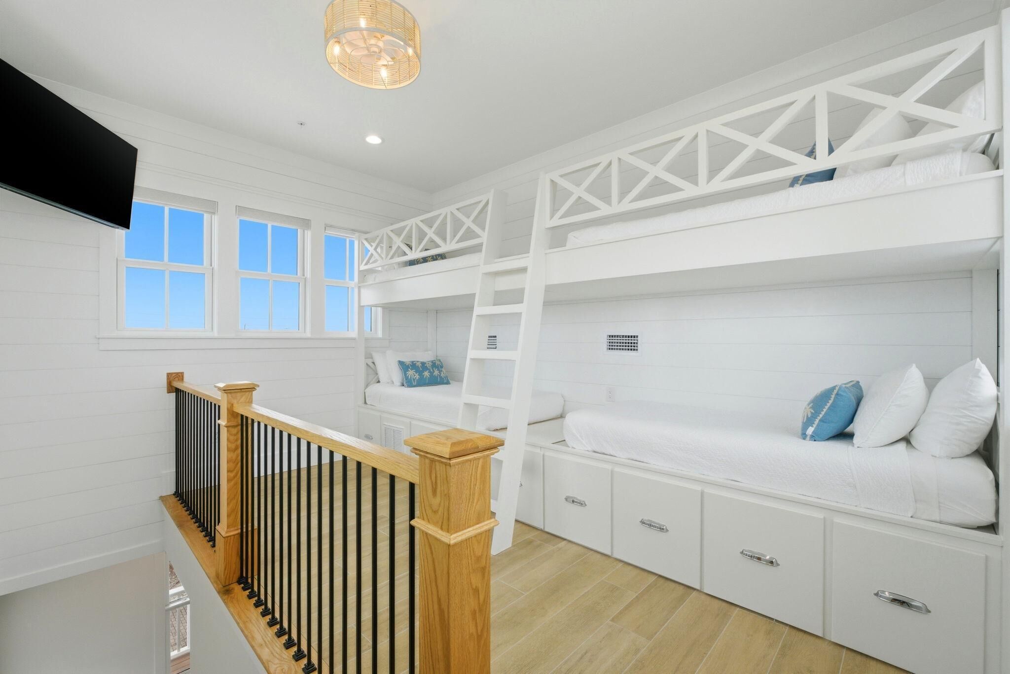 A room with bunk beds, a wooden railing, and a television.