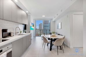 Eine moderne Küche mit Essbereich, Blick auf die Stadt und einem Balkon.