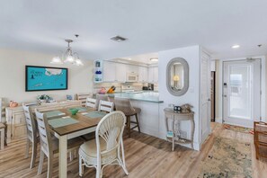 A modern kitchen with white cabinets, a central island, and a dining area with a wooden table and wicker chairs. - P48 - 2 Bedroom, 2 Bath Beach front condo with pool (Marathon)