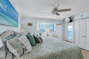 A bedroom with a bed, a ceiling fan, a window with blinds, a door, and a view of the ocean. - P48 - 2 Bedroom, 2 Bath Beach front condo with pool (Marathon)
