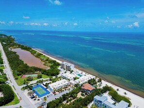 An aerial view of a coastal hotel with multiple buildings, a beach, and clear blue waters. - P48 - 2 Bedroom, 2 Bath Beach front condo with pool (Marathon)