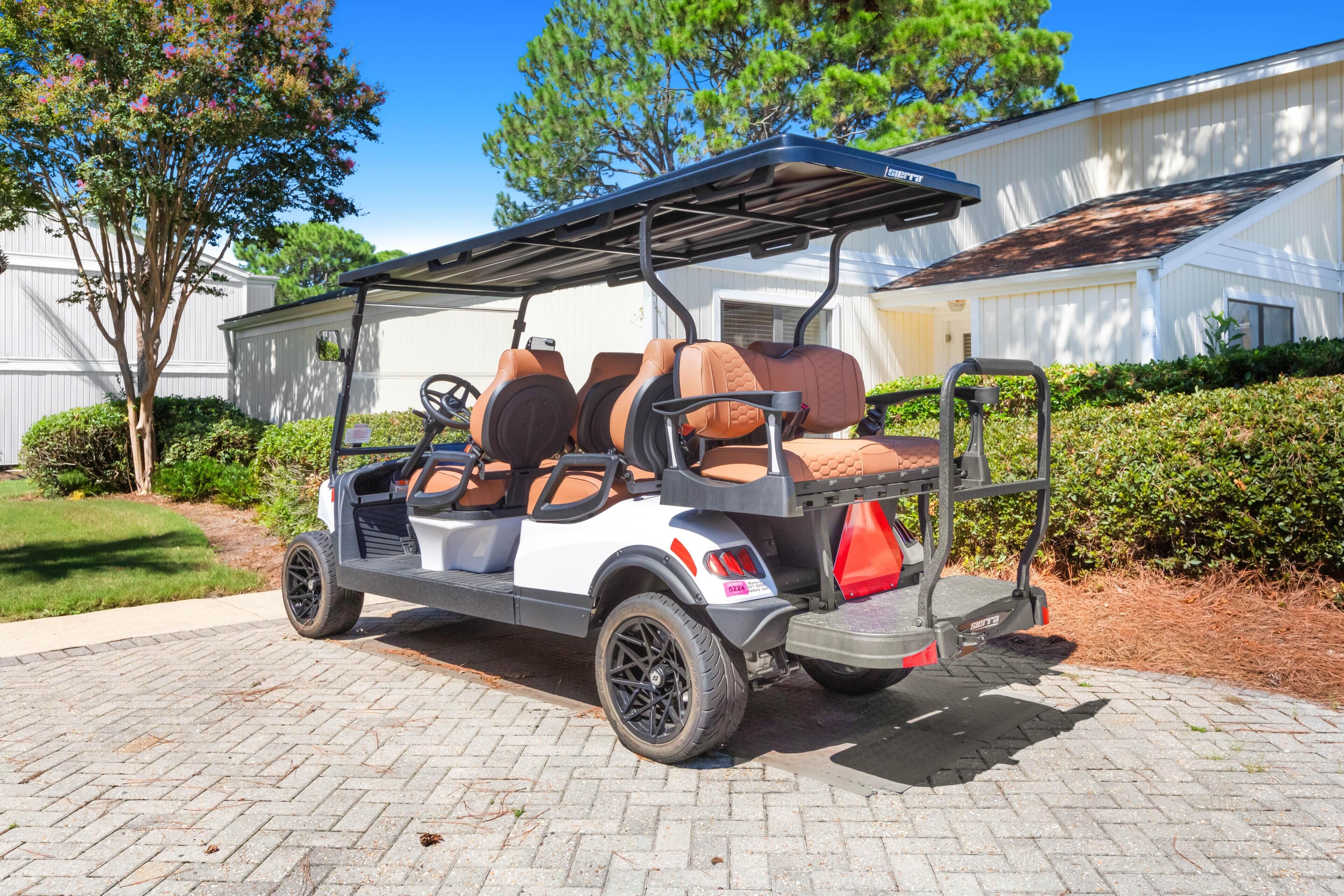 Um carrinho de golfe com toldo, estacionado em um caminho de concreto.