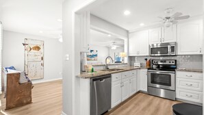 Een moderne keuken met witte kastjes, roestvrijstalen apparatuur en een houten vloer.