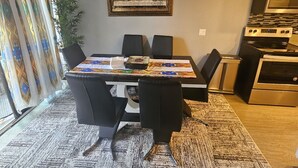 A dining area with a table, chairs, a ceiling fan, a painting, and a kitchen with appliances. - Beautiful stylish vacation, Dream home (Kent)