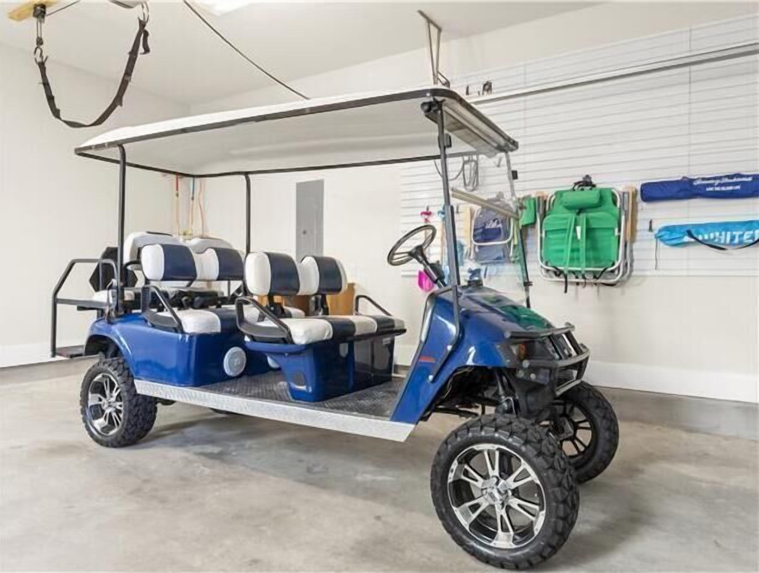 A blue golf cart with a canopy, parked indoors with a concrete floor and white walls.