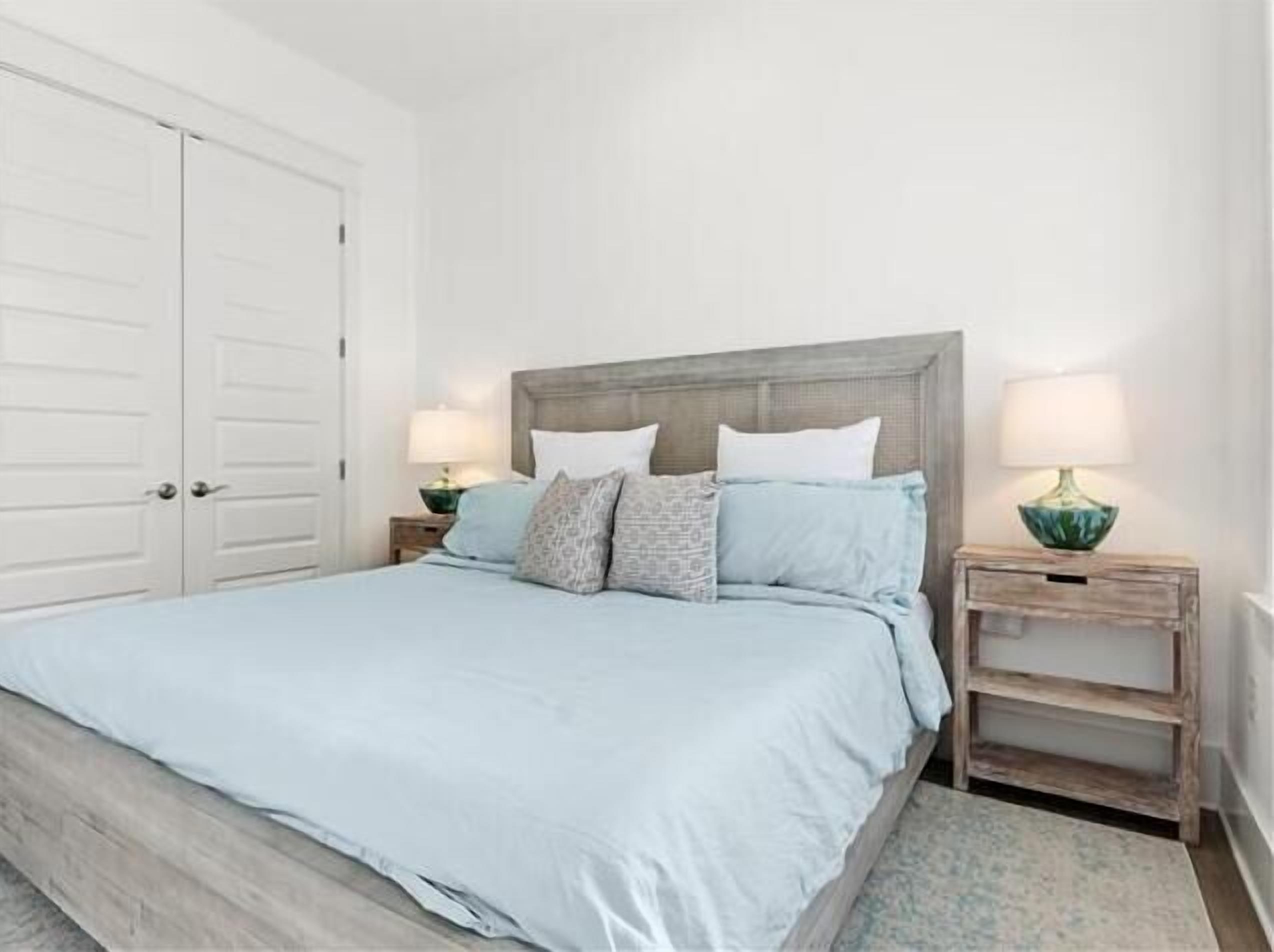 A bedroom with a bed, two nightstands, a lamp, and a door.