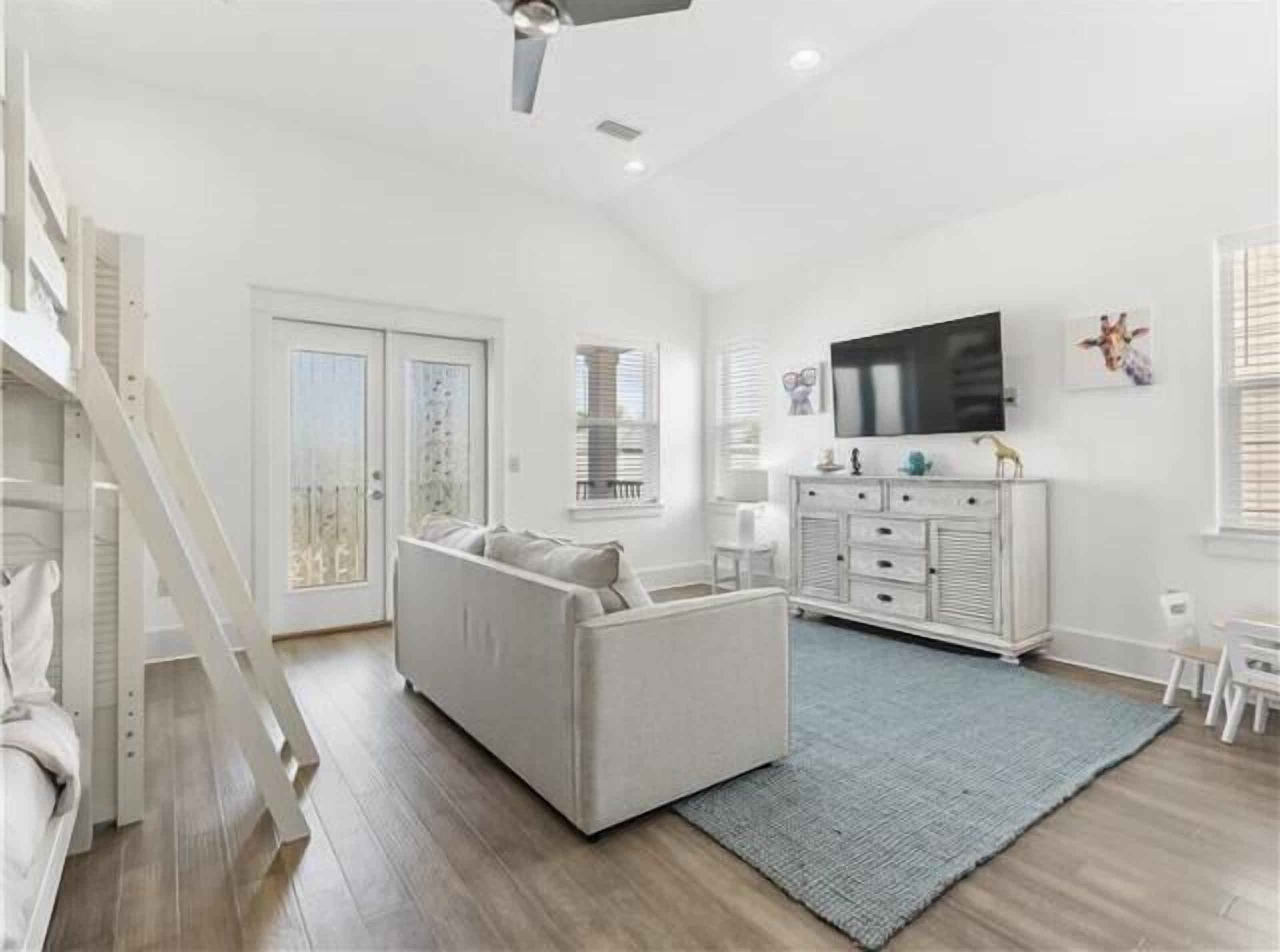 A spacious living room with a large TV, a sofa, and a staircase.